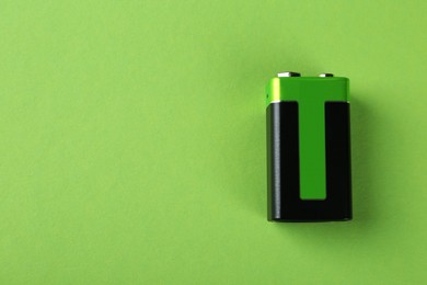 Image of New nine volt battery on light green background, top view. Space for text