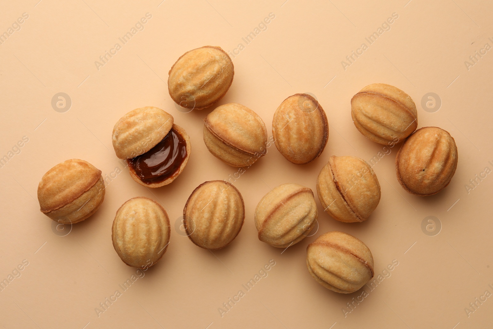 Homemade walnut shaped cookies with boiled condensed milk on beige background, flat lay Photo of Homemade walnut shaped cookies with boiled condensed milk on beige background, flat lay