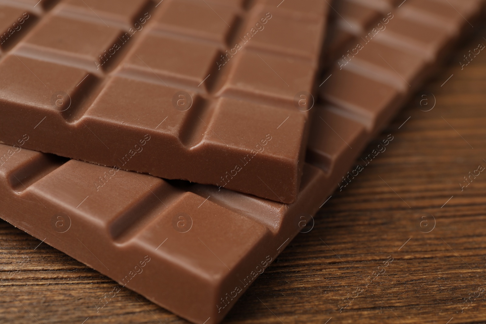 Photo of Tasty chocolate bars on wooden table, closeup