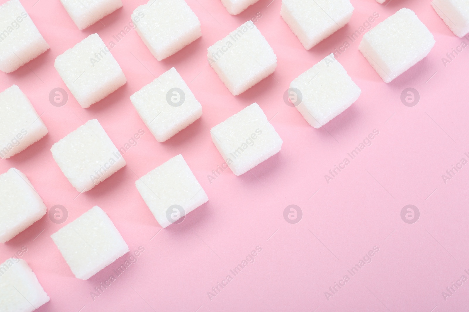 White sugar cubes on pink background, top view. Space for text Photo of White sugar cubes on pink background, top view. Space for text