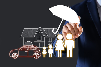 Image of Insurance concept - umbrella demonstrating protection. Man using virtual screen with illustrations, closeup