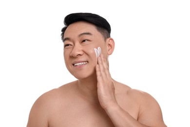 Photo of Handsome man applying cream onto his face on white background