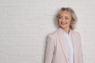 Photo of Portrait of mature woman near brick wall. Space for text