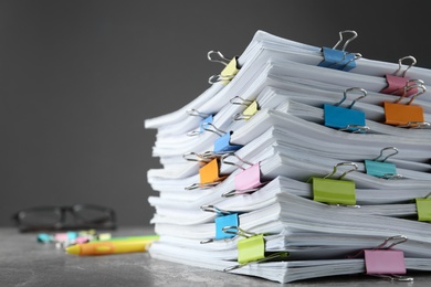 Photo of Stack of documents with binder clips on grey stone table, closeup view. Space for text