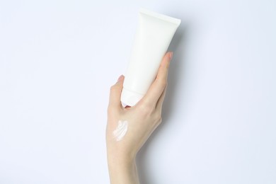 Photo of Woman with tube of cream on white background, closeup