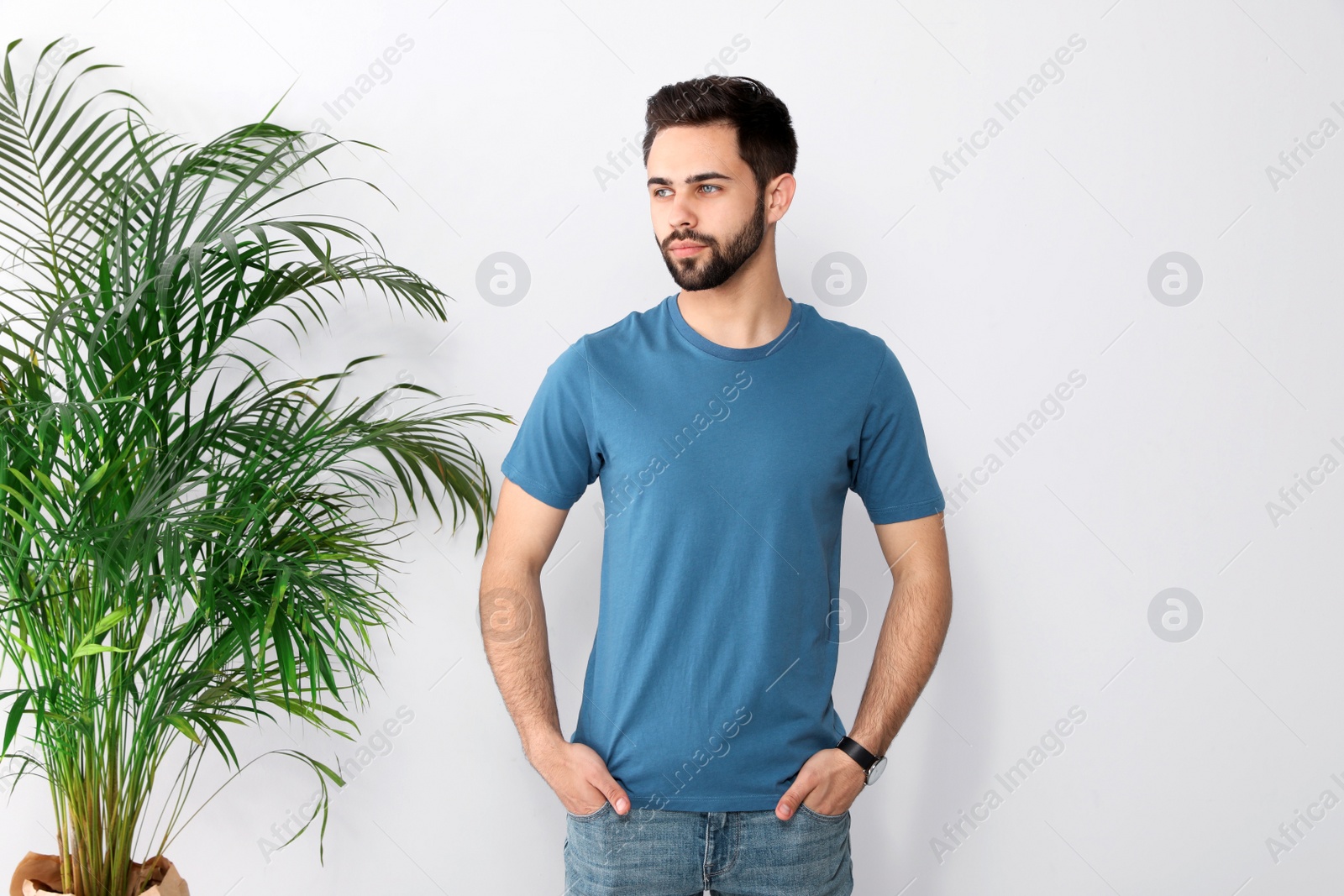 Photo of Young man in t-shirt near light wall. Mock up for design