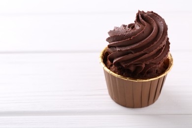 Photo of Delicious chocolate cupcake on white wooden table, closeup. Space for text