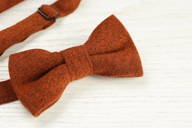 Photo of Stylish terracotta bow tie on white wooden background, closeup