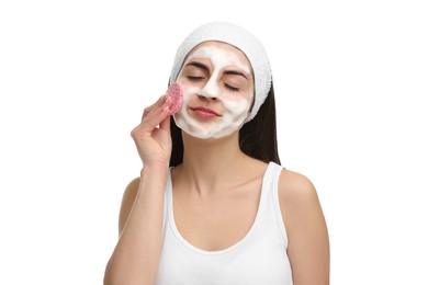 Photo of Young woman with headband washing her face using sponge on white background