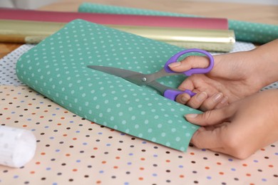 Photo of Woman cutting fabric with scissors at table, closeup
