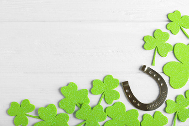 Photo of Flat lay composition with clover leaves on white wooden table, space for text. St. Patrick's Day celebration