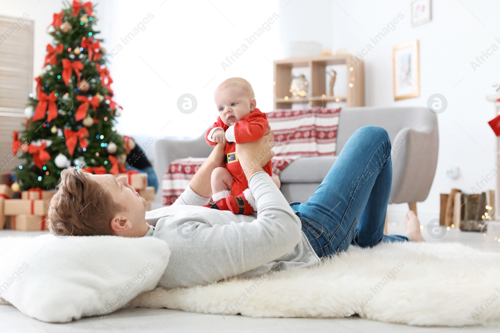 Photo of Young man with baby in Christmas suit at home