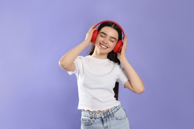 Photo of Teenage girl listening music with headphones on violet background