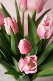 Photo of Bouquet of beautiful spring tulips on light pink background, closeup