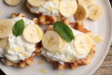 Photo of Delicious Belgian waffles with banana and whipped cream on table, top view