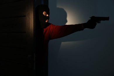 Thief with gun entering foreign house at night. Burglary