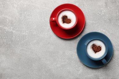 Photo of Cups of aromatic coffee with heart shaped decoration on light grey table, flat lay. Space for text