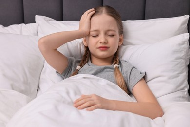 Photo of Little girl suffering from headache in bed