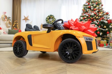Photo of Children's electric toy car with red bow in room decorated for Christmas