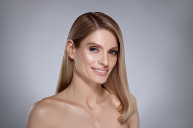 Image of Portrait of attractive woman with blonde hair smiling on grey background