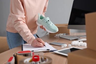 Photo of Shoes seller working at table in office, closeup. Online store