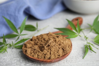 Photo of Hemp protein powder and fresh leaves on light grey table, closeup