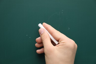 Photo of Teacher writing with chalk on green chalkboard, closeup. Space for text