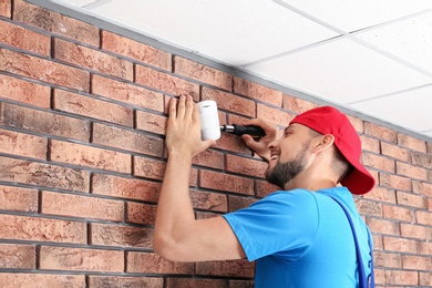 Photo of Male technician installing alarm system indoors