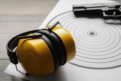 Photo of Shooting target, headphones and handgun on table, closeup