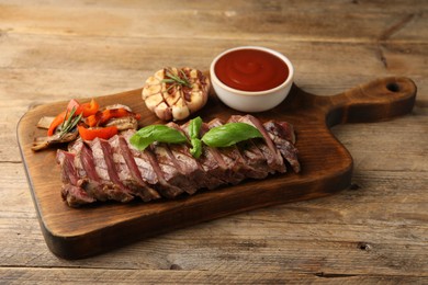 Photo of Delicious grilled beef steak with spices and tomato sauce on wooden table