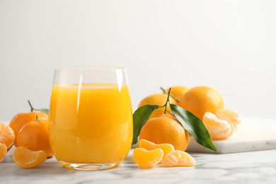 Photo of Glass of fresh tangerine juice and fruits on marble table