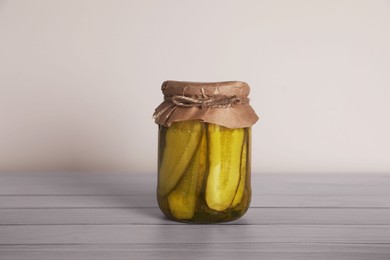 Photo of Jar with pickled cucumbers on white wooden table