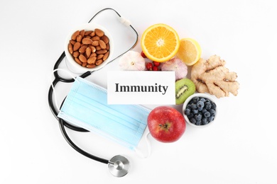 Photo of Set of natural products, stethoscope, face mask and card with word Immunity on white background, top view