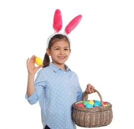 Photo of Little girl in bunny ears headband holding basket with Easter eggs on white background