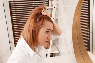Photo of Woman suffering from baldness near mirror at home