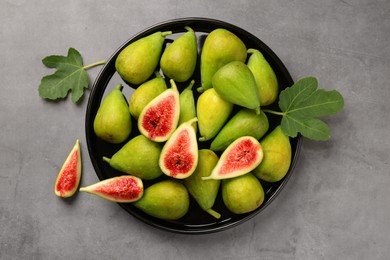 Photo of Cut and whole green figs on light gray table, top view