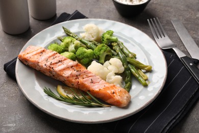 Photo of Healthy meal. Piecegrilled salmon, vegetables, asparagus and rosemary served on grey textured table, closeup