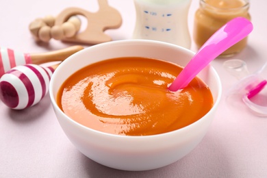 Photo of Healthy baby food in bowl on light table, closeup