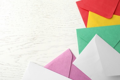 Photo of Colorful paper envelopes on white wooden background, flat lay. Space for text