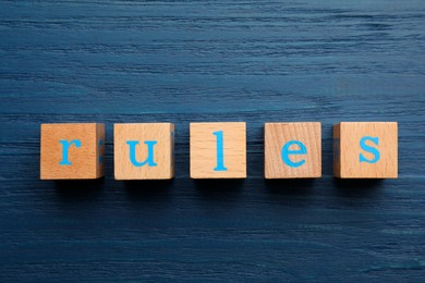 Photo of Word Rules made of cubes with letters on blue wooden table, top view