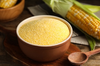 Photo of Cornmeal in bowl on wooden table, closeup