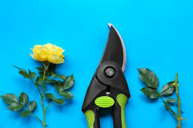 Photo of Secateur and beautiful yellow rose on light blue background, flat lay