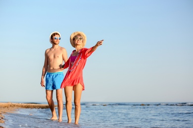 Photo of Happy young couple walking together on beach. Space for text