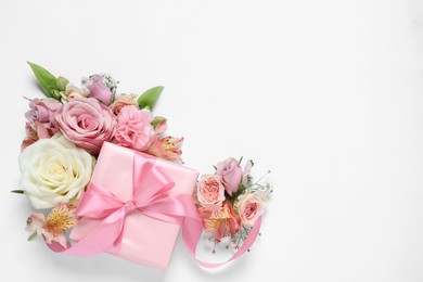 Photo of Gift box and beautiful flowers on white background, flat lay. Space for text