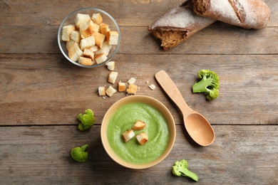 Photo of Flat lay composition with bowl of broccoli cream soup on wooden table