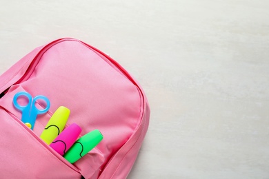 Photo of Backpack with school stationery on light background, top view and space for text