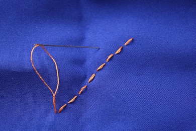 Photo of Sewing needle with thread and stitches on blue cloth, above view