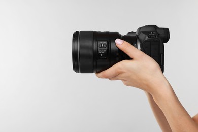 Photo of Photographer with camera on light grey background, closeup. Space for text