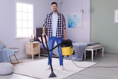 Photo of Mature man hoovering carpet with vacuum cleaner at home