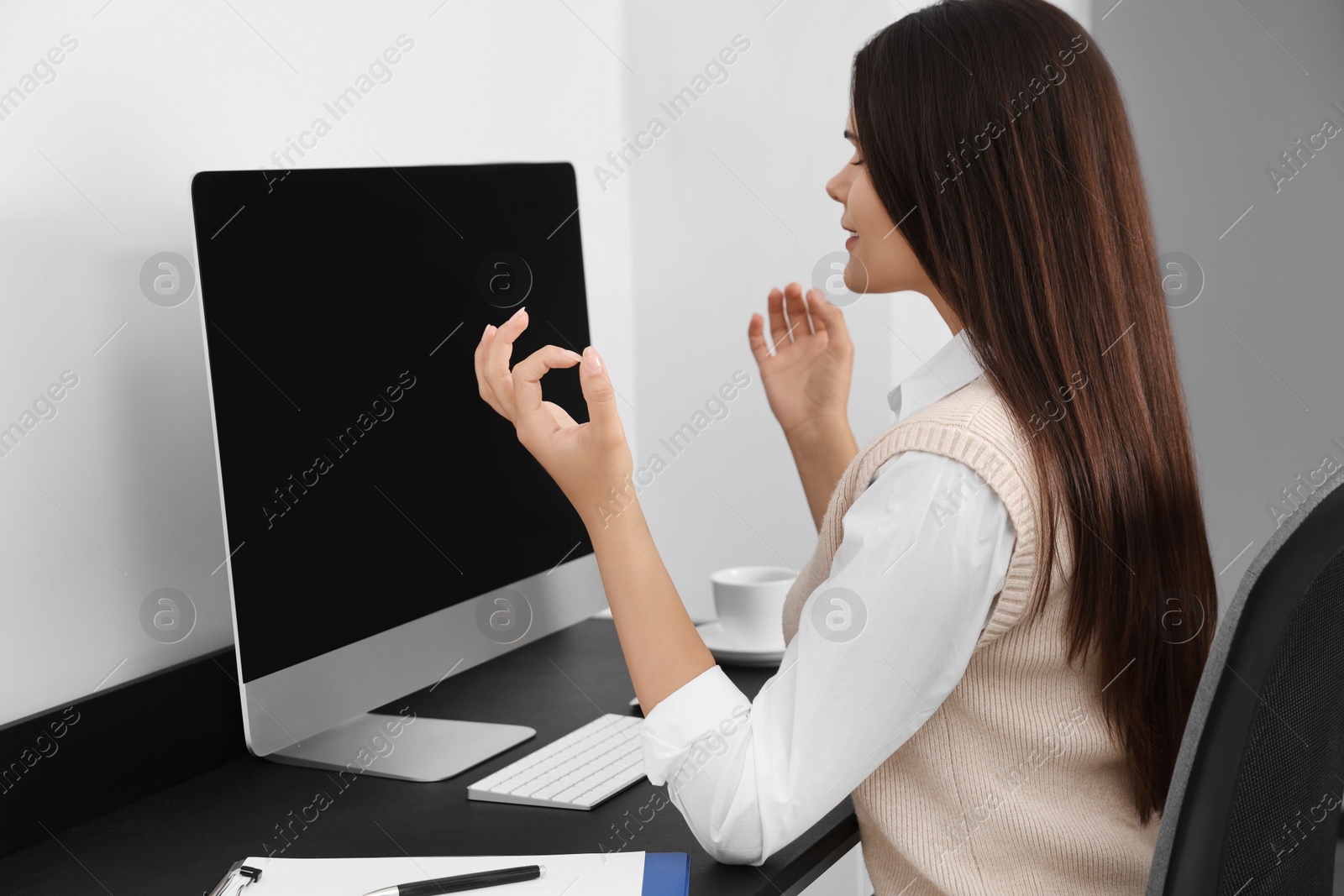 Photo of Young businesswoman meditating at workplace. Zen concept